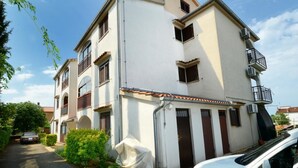 A two-story residential building with a white facade, multiple balconies, and a covered entrance. - Apartment 297 (Porec)