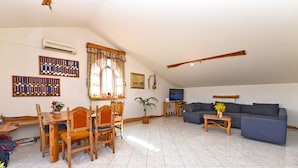 A living room with a dining area, a sofa, a TV, and a wooden table. - Apartment 316 (Fazana)
