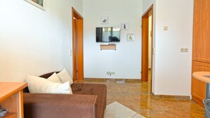 A living room with a brown sofa, a TV mounted on the wall, and a wooden cabinet. - Apartment 336 (Porec)