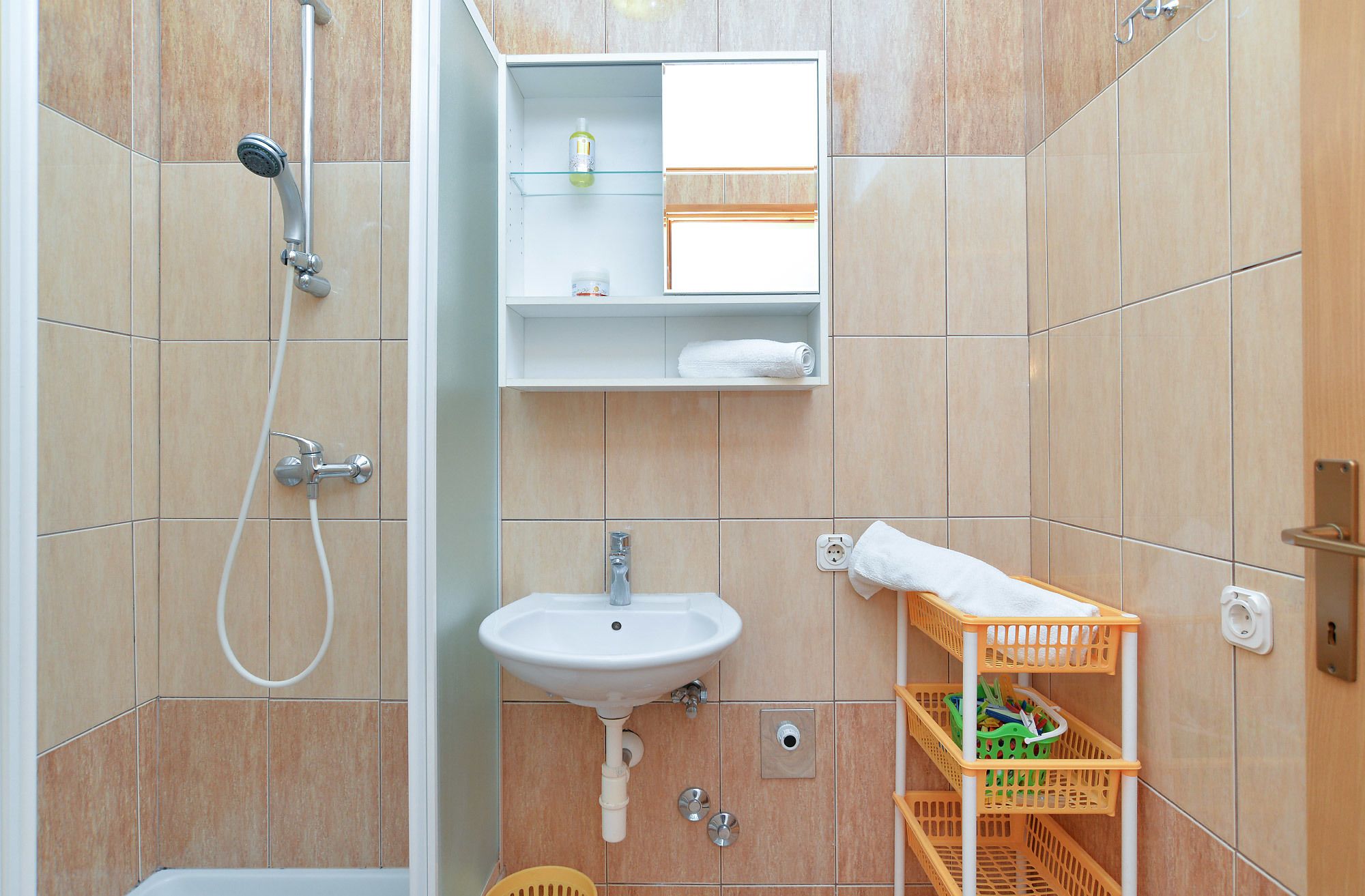 Une salle de bain avec une douche, un lavabo et une étagère contenant des articles de toilette.