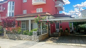 A two-story building with a red facade, white shutters, and a balcony with white railings. - Apartment 356 (Umag)
