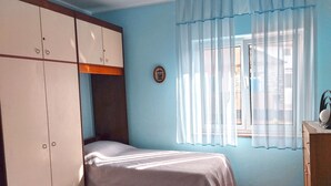 A bedroom with a bed, a wardrobe, a window with curtains, and a wooden floor. - Apartment 356 (Umag)