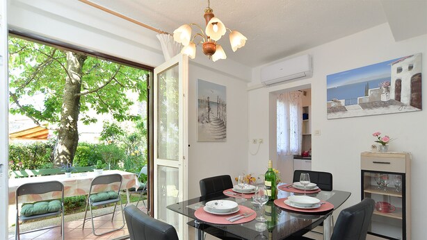 Un coin repas avec une table en verre, des chaises noires et une vue sur l’extérieur.
