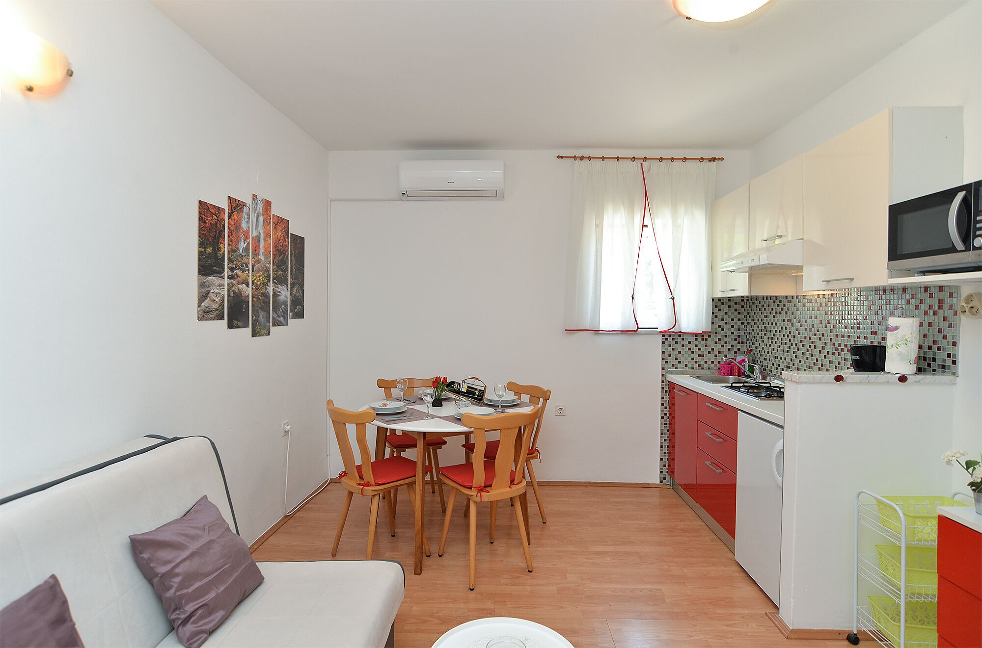 Una cocina compacta con comedor, un sofá y un televisor.