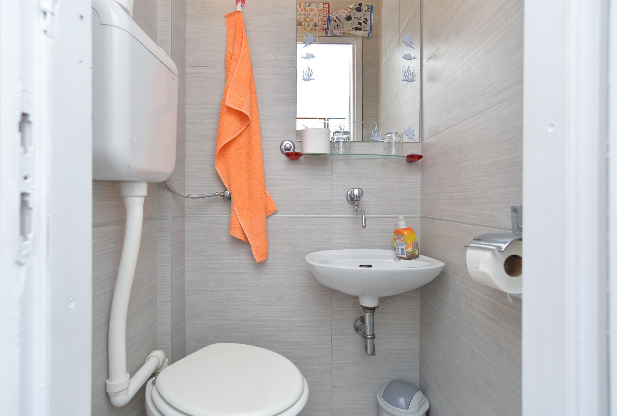 A small bathroom with a toilet, sink, and mirror.