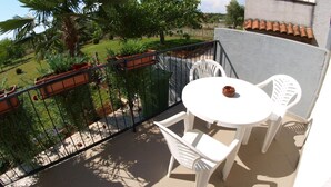Ein Balkon mit weißem Tisch und Stühlen, umgeben von einem Metallgeländer.