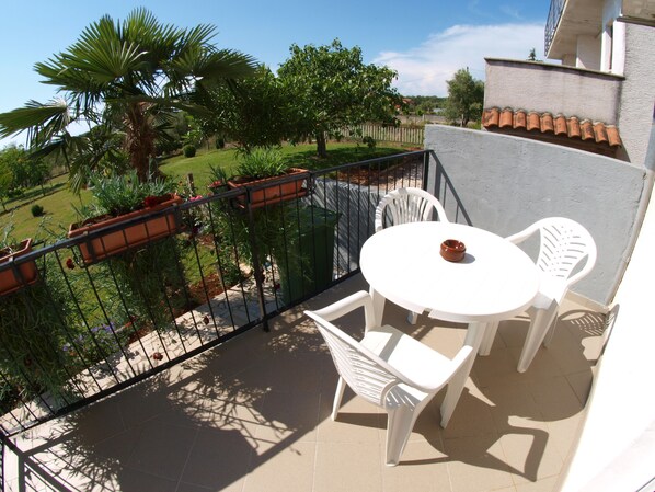 Enjoy a peaceful retreat on this balcony overlooking a lush garden with a palm tree.