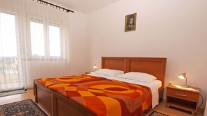 Ein Hotelzimmer mit einem Bett, zwei Nachttischen, einer Lampe, einem Bild an der Wand und zwei Teppichen.