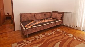 Ein Eckzimmer mit einem braunen Sofa, einem gemusterten Teppich und einer Heizung.