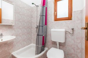 Une salle de bain équipée d’une douche, de toilettes, d’un lavabo et d’une fenêtre.