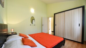 Ein Schlafzimmer mit einem Bett, einem Nachttisch, einem Spiegel und einem Kleiderschrank.
