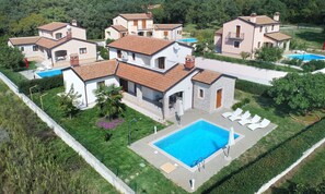 Zona residencial con varias casas, una piscina y un jardín bien cuidado.