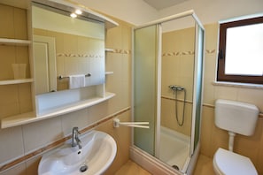 Un bagno con lavandino, specchio, doccia e WC.