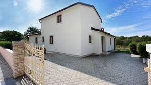 Ein zweistöckiges Haus mit einem sechseckig gefliesten Auffahrt und einem Eingangstor.