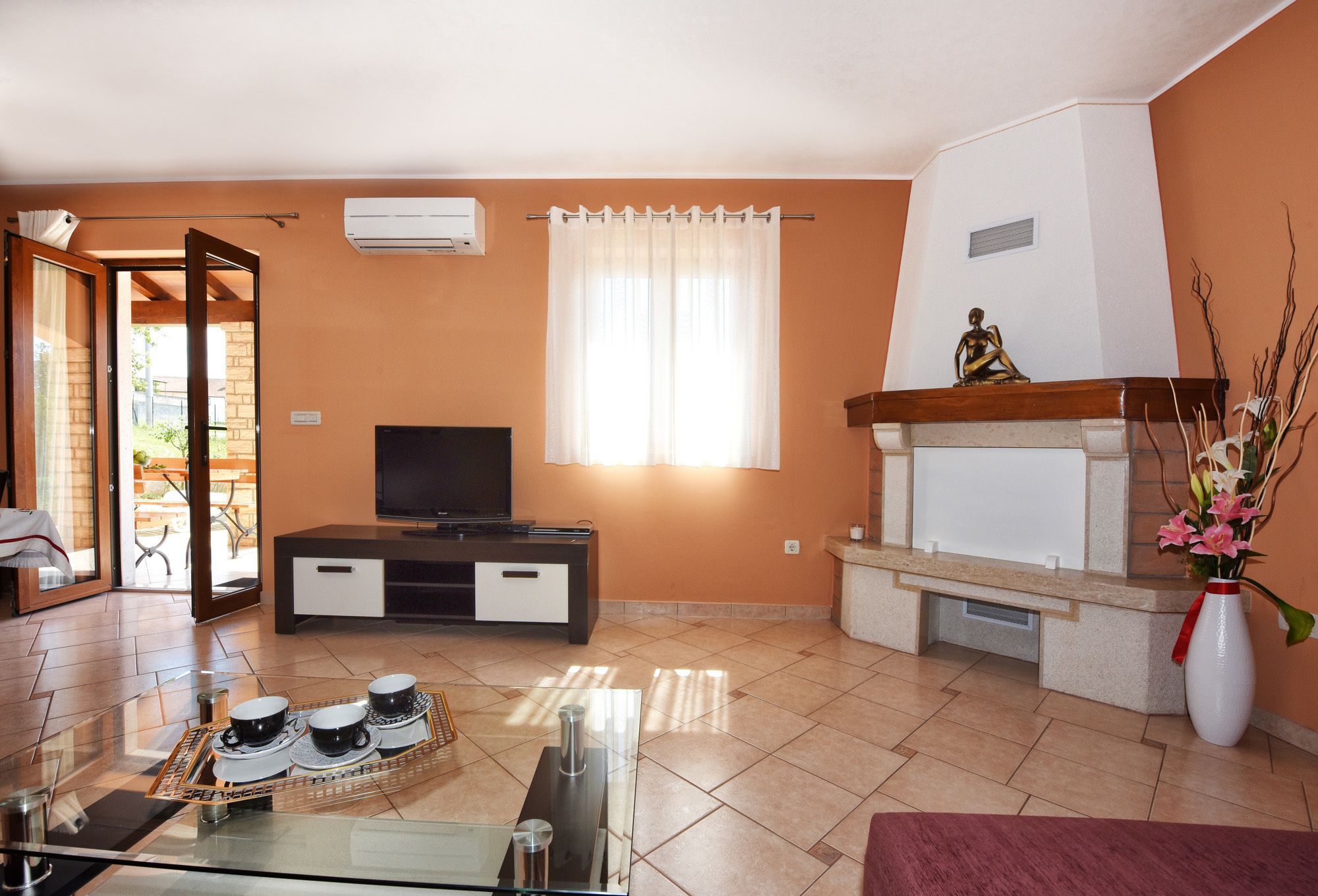 A living room with a TV, a fireplace, and a dining area with a table and chairs.