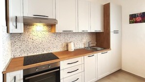 Eine moderne Küche mit weißen Schränken, einer Holz Arbeitsplatte und einem eingebauten Backofen.