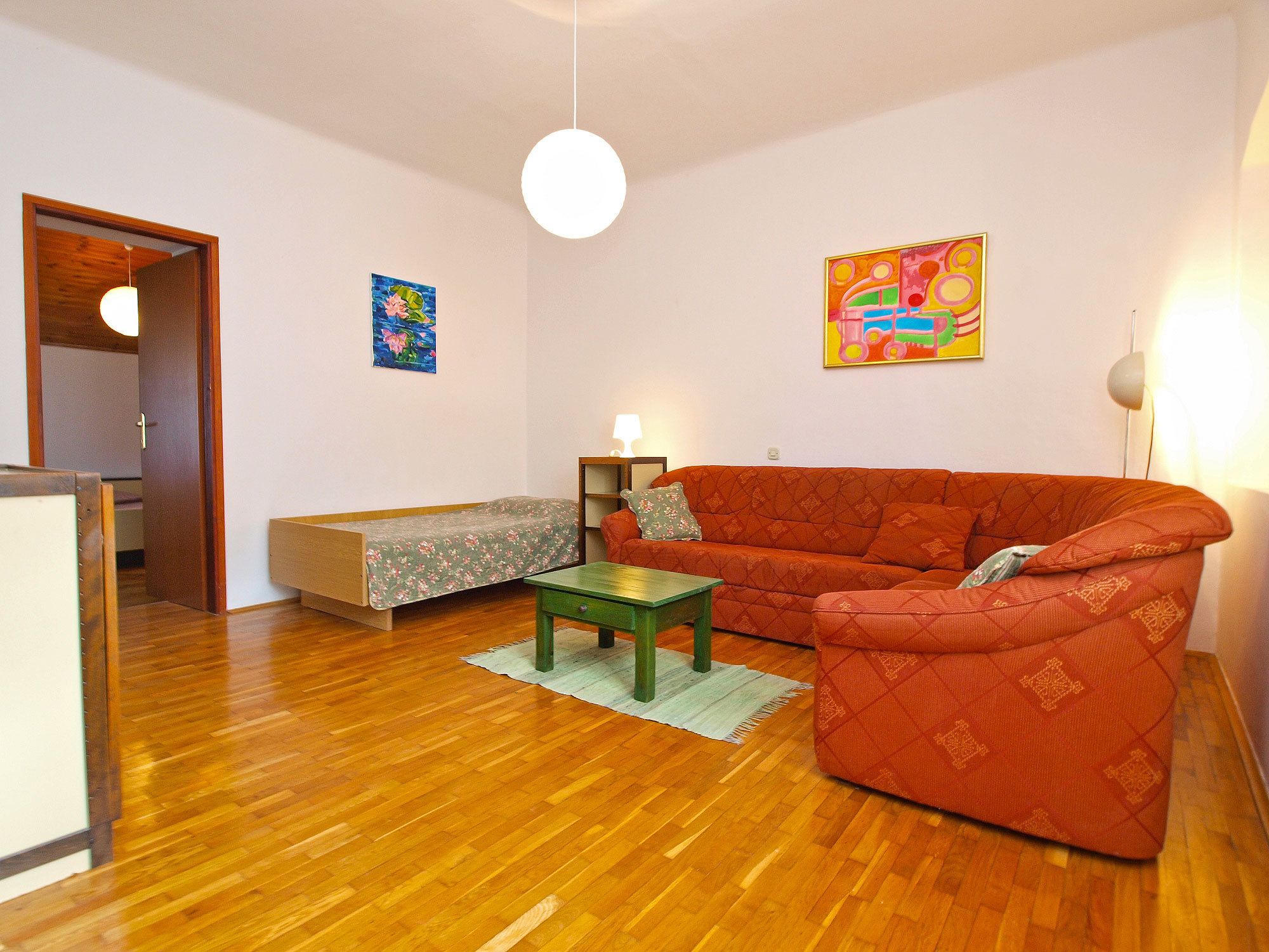 A living room with a sofa, a small table, a lamp, and artwork on the walls.