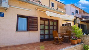 A residential building with a tiled patio, a wooden table and chairs, and a stone wall. - Apartment 389 (Pula)