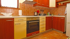 A kitchen with wooden cabinets, a stove, and a sink. - Apartment 389 (Pula)
