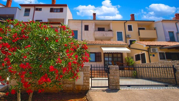 A row of Mediterranean-style buildings with terracotta roofs, a stone wall, and a gate. - Apartment 389 (Pula)