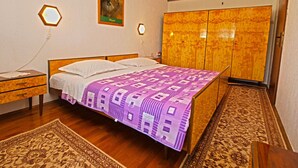 Ein Schlafzimmer mit Bett, Schrank, Nachttisch, einem Gemälde und einer sechseckigen Lampe.