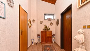 Un pasillo con puerta de madera, un armario, una estatua y una alfombra estampada.
