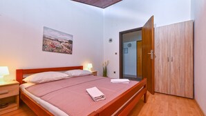 Un dormitorio con cama de madera, lámparas de noche, un cuadro, un armario y un espejo.