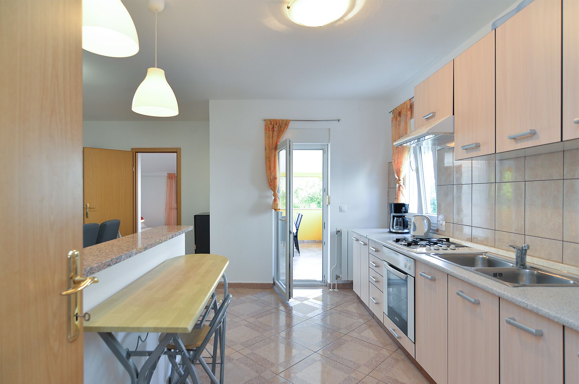 A compact kitchen with a built-in oven, a coffee maker, and a sink.