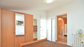 A bedroom with a bed, wooden wardrobe, and a door leading to another room. - Apartment 436 (Fazana)