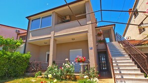 A two-story building with a balcony, a staircase, and a garden with flowers. - Apartment 439 (Fazana)
