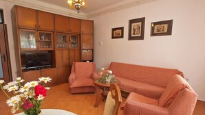 A living room with a sofa, armchairs, a TV, wooden cabinets, and framed pictures on the wall. - Apartment 439 (Fazana)