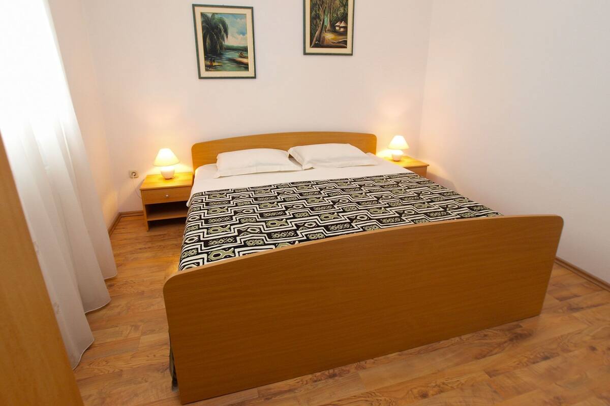 Un dormitorio con una cama de madera, dos lámparas de noche y dos cuadros en la pared.