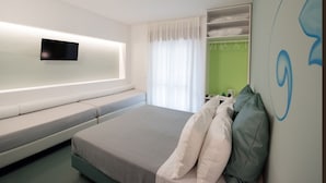 A modern hotel room with a bed, a flat-screen TV mounted on the wall, a green wall, and a window with white curtains. - B&B Oikos Selinunte (Castelvetrano)