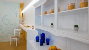 A kitchen with white cabinetry, blue glassware, and a fruit bowl. - B&B Oikos Selinunte (Castelvetrano)