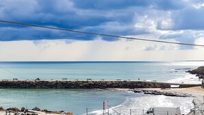 A coastal view with a rocky pier, calm sea, and a clear sky. - B&B Oikos Selinunte (Castelvetrano)