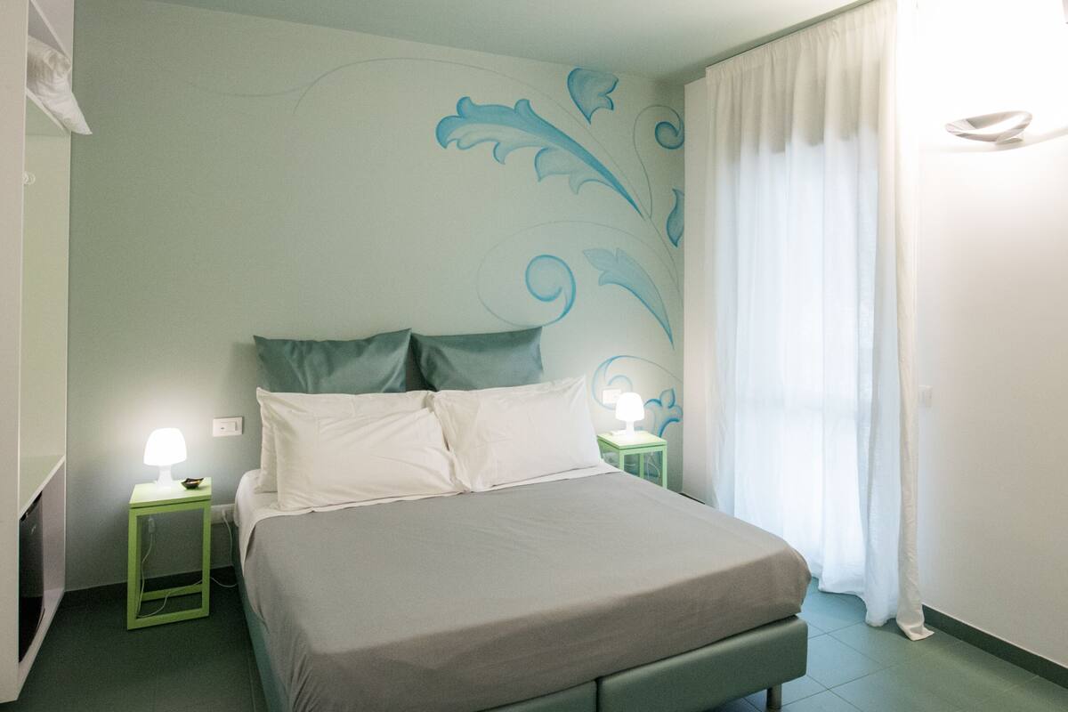 A neatly arranged bedroom with a bed, bedside tables, and a wall mural.