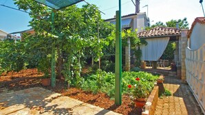 Ein Garten mit einer Pergola, Blumentöpfen und einem Pflasterweg.