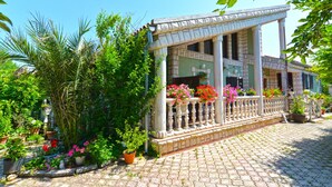 A building with a covered porch, stone columns, and potted plants. - Apartment 498 (Medulin)
