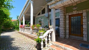 A stone building with a covered porch, potted plants, and a wooden door. - Apartment 498 (Medulin)