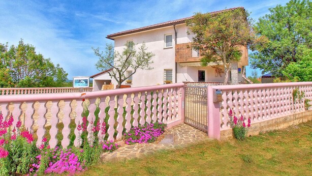 A two-story house with a stone facade, a pink fence, and a garden with pink flowers. - Apartment 517 (Pula)