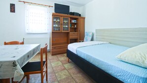 A bedroom with a bed, a wooden cabinet, a table, and a chair. - Apartment 517 (Pula)