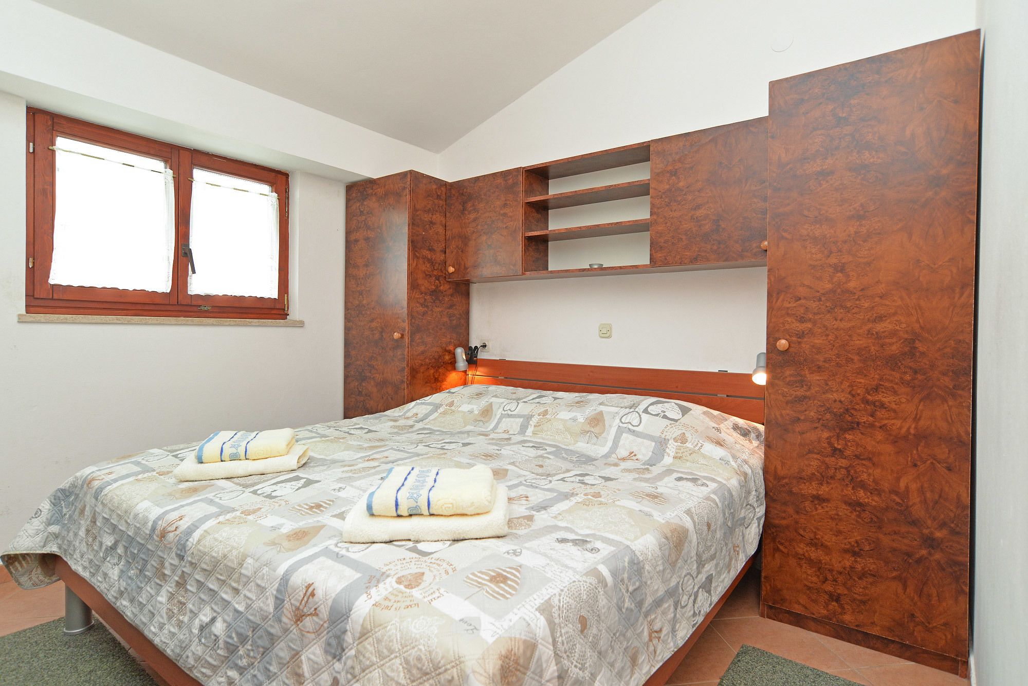 A bedroom with a bed, a window, and wooden furniture.