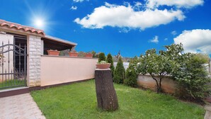 Une propriété résidentielle dotée d’une façade en pierre, d’une terrasse carrelée et d’une pelouse bien entretenue.