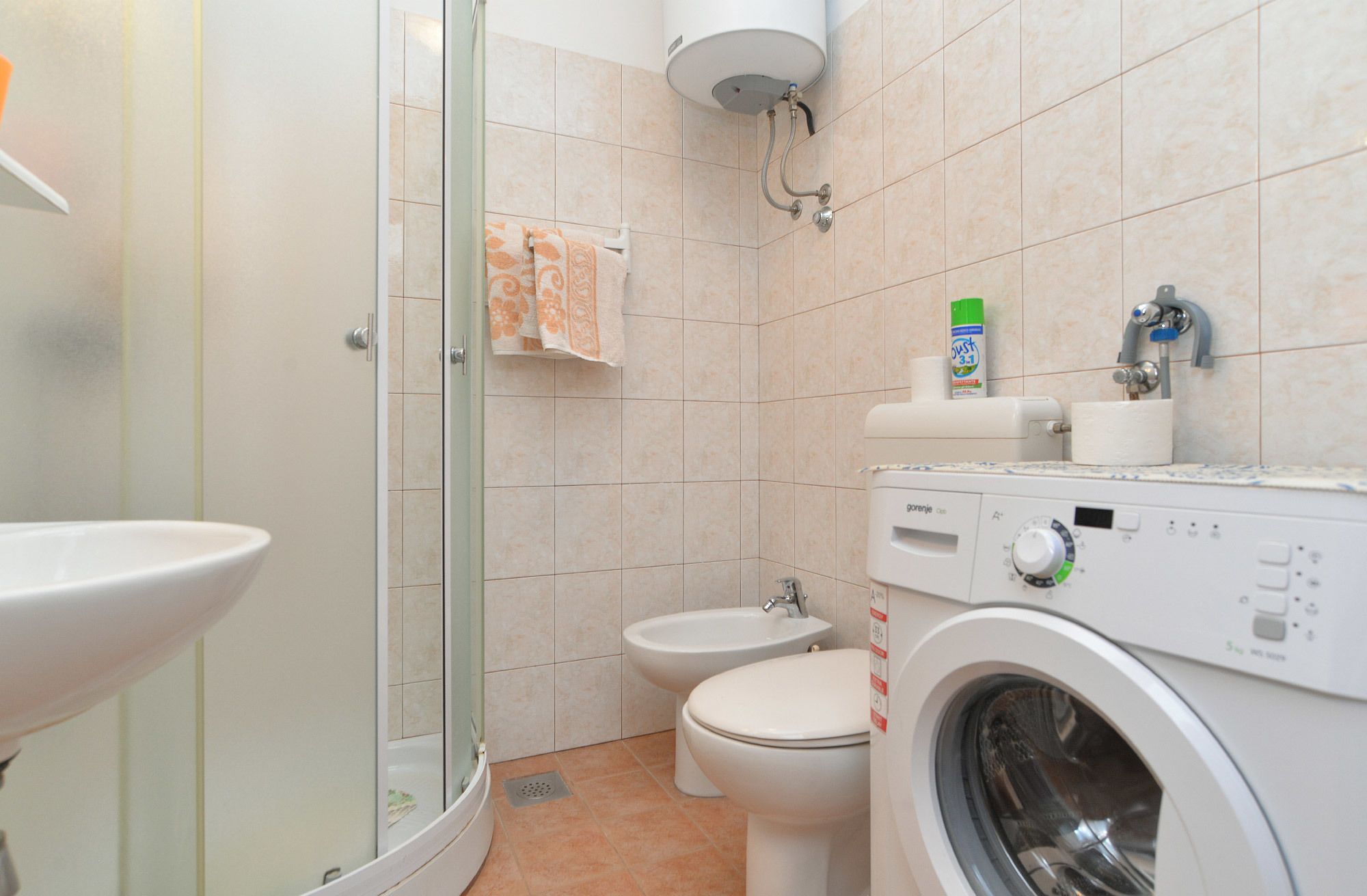 A bathroom with a glass-enclosed shower, a toilet, a bidet, and a washing machine.
