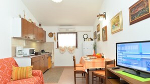 Un espace de vie compact comprenant un coin cuisine, un coin repas et un téléviseur posé sur un bureau en bois.
