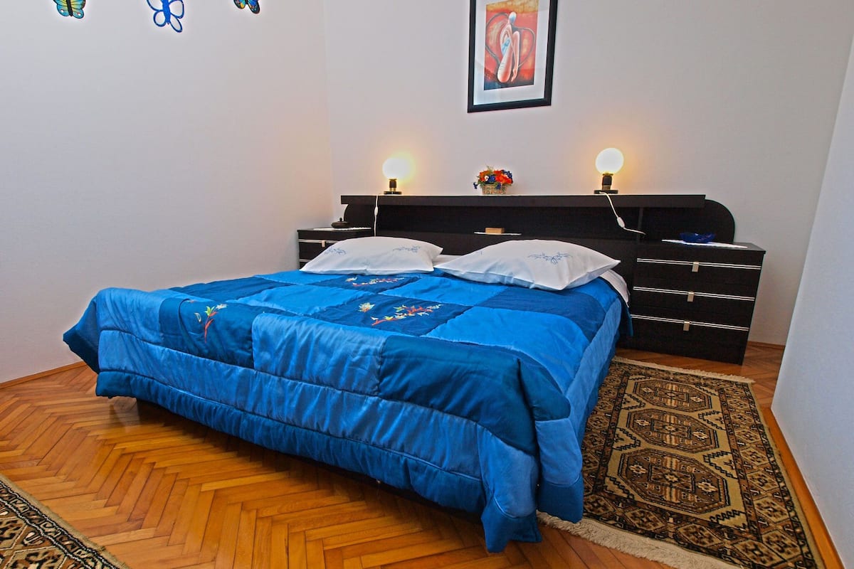 Quarto com cama, penteadeira, tapete e decorações nas paredes.