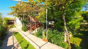 A pathway leading to a building with a red staircase and a pergola covered in vines. - Apartment 531 (Pula)