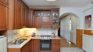 A kitchen with wooden cabinets, a gas stove, a dishwasher, and a tiled backsplash. - Apartment 531 (Pula)