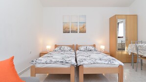 Ein Doppelbett mit einem Bettbezug in Marmoroptik, zwei Nachttische mit Lampen und ein Holzschrank mit Spiegel.
