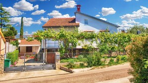 Ein Wohngebäude mit rotem Ziegeldach, weißer Fassade und einem Garten mit verschiedenen Pflanzen.